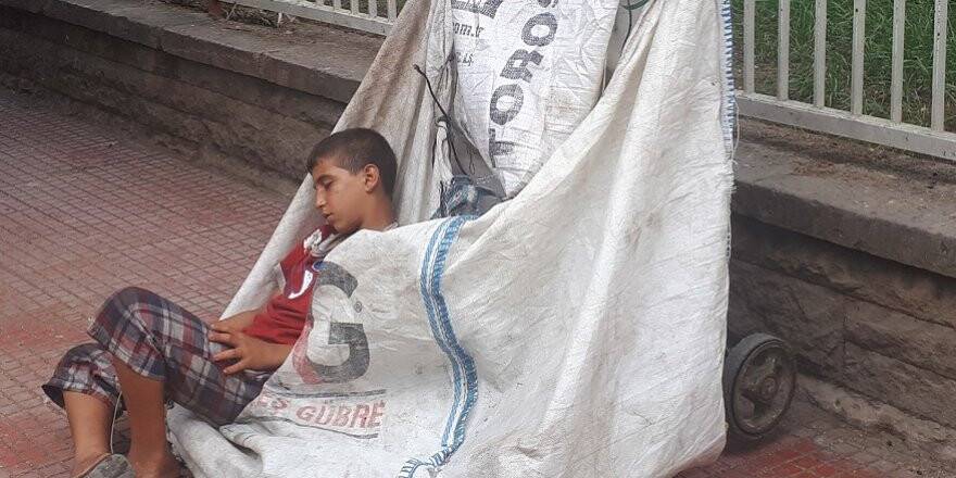 Sıcaktan yorgun düşen kağıt toplayıcısı küçük çocuk el arabasında uyuya kaldı
