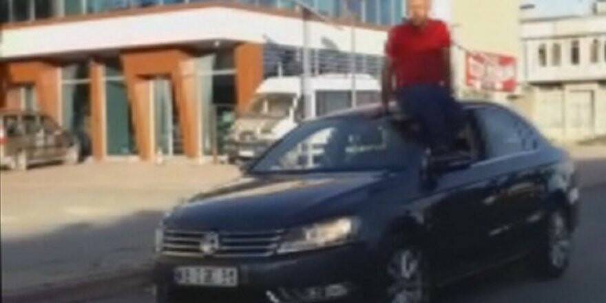 Otomobilin tavanına oturup, direksiyonu ayağıyla kontrol ederek araç kullandı