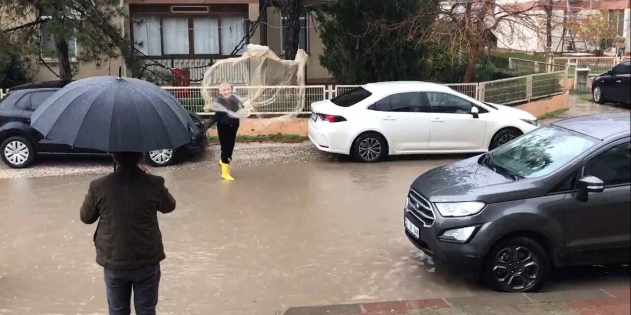 Göle dönen yollarda ağ atıp balık tutmaya çalıştı