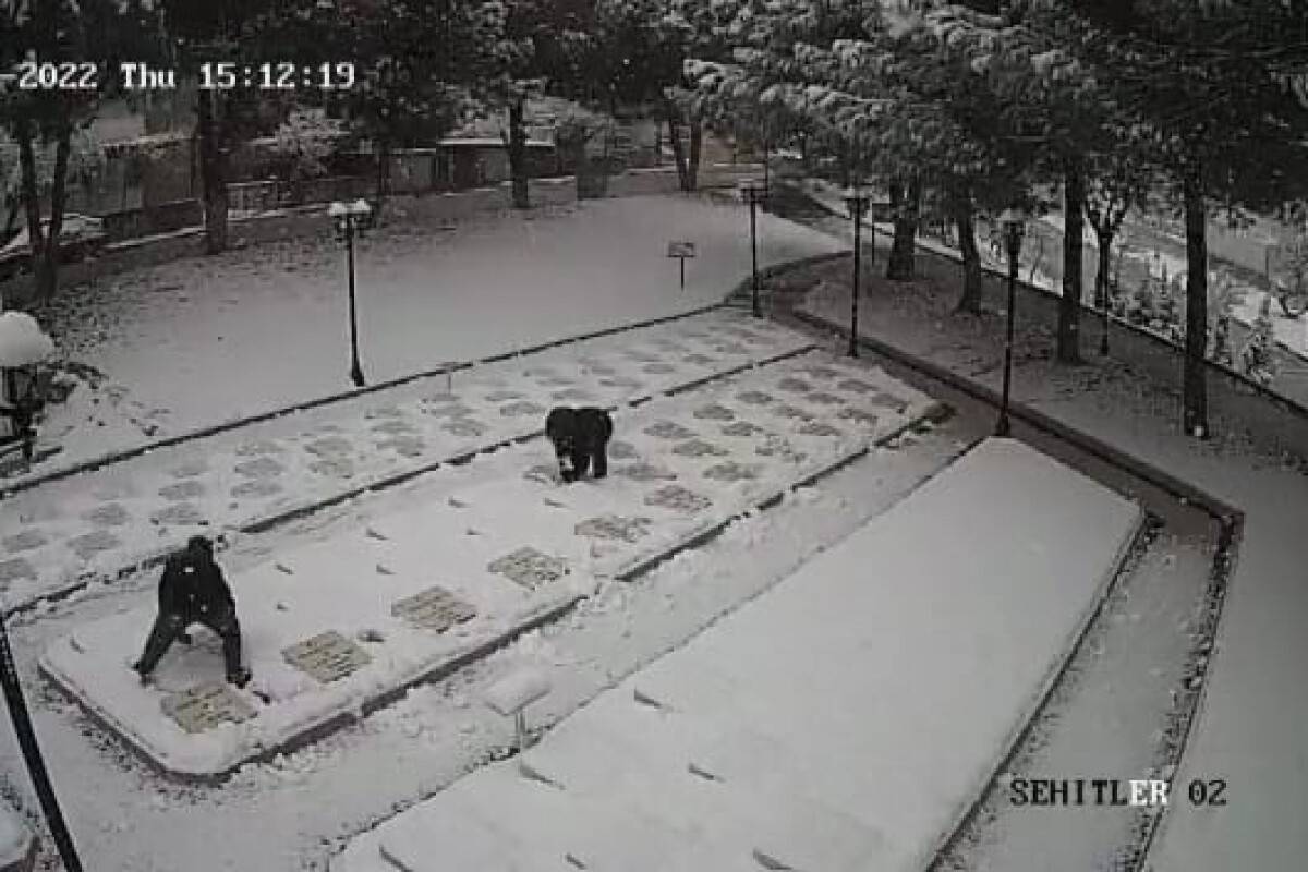 2 çocuk karla kaplanan şehitlikteki mezar taşlarını temizledi