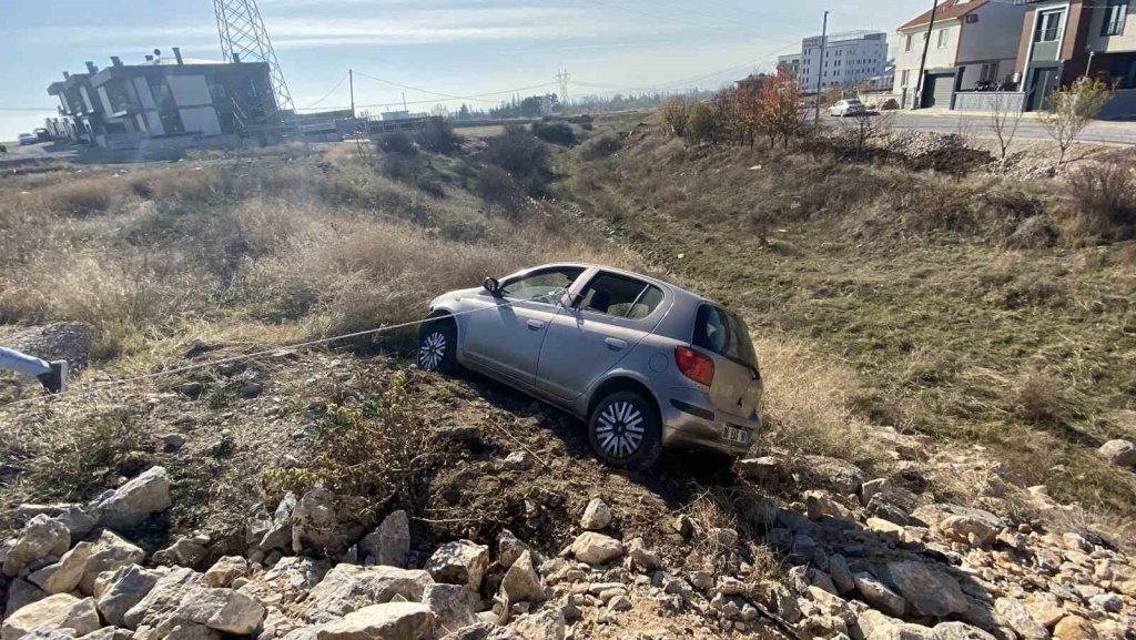 Yoldan çıkan otomobil taşlık alanda asılı kaldı